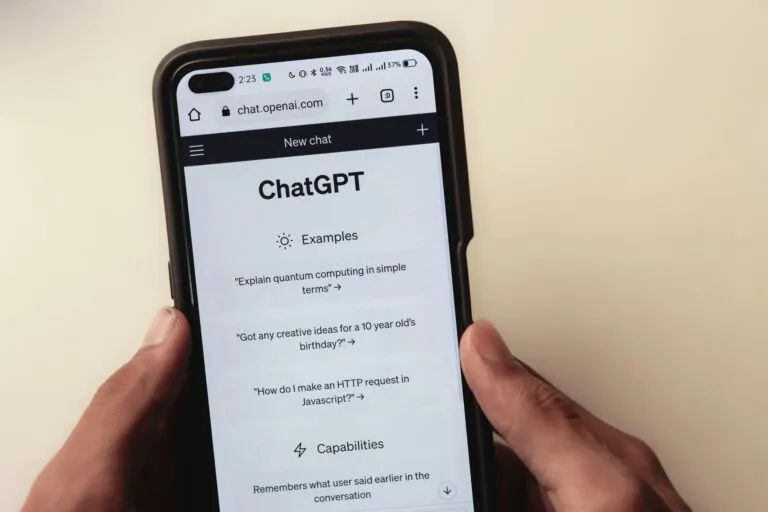 A person holds a cell phone open to a ChatGPT webpage, which is prompting the user to ask a series of questions.